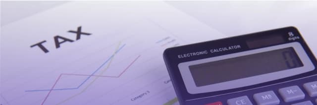 Close-up of a tax document with colorful line charts and a calculator, symbolizing financial analysis under soft purple lighting.