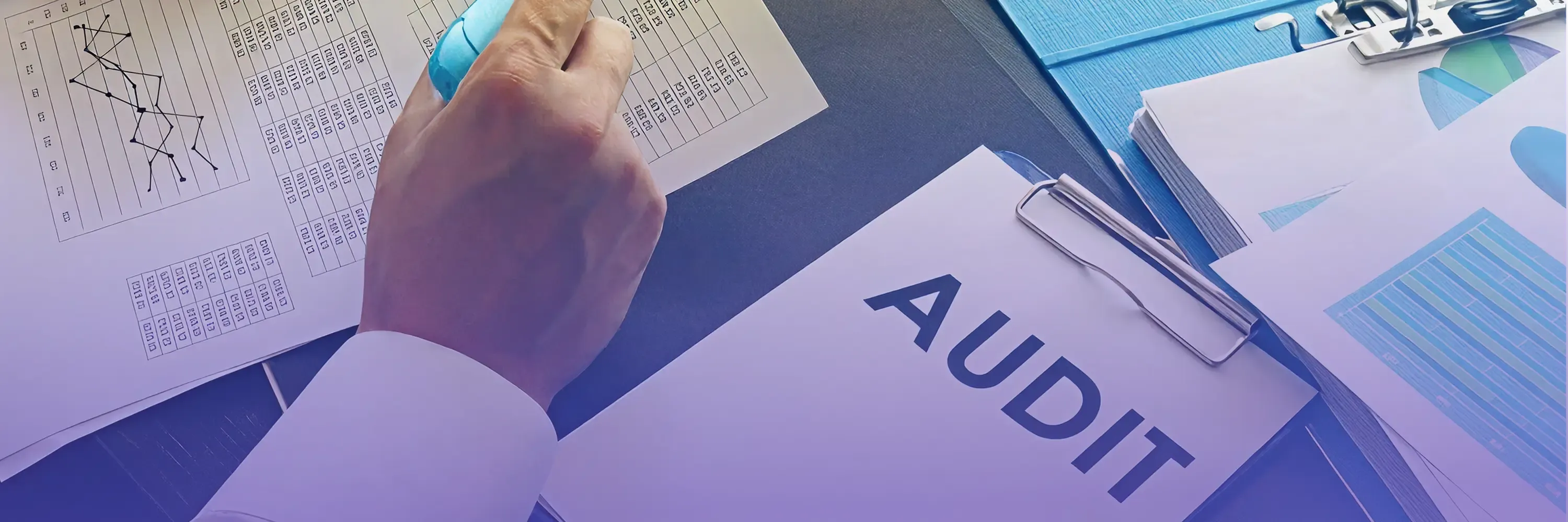 Close-up of a person reviewing audit documents with charts and a clipboard labeled “AUDIT,” symbolizing financial analysis and compliance.