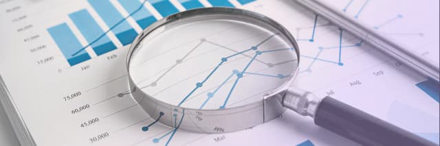 Magnifying glass placed over financial charts and graphs symbolizing data accuracy and compliance review in professional tax filing services.