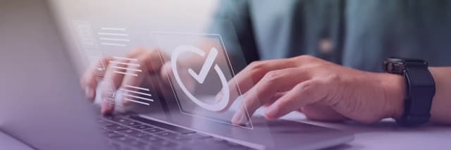 A person typing on a laptop with a transparent digital interface showing a checkmark symbol that represents verification, compliance, and secure approval processes