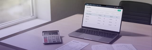 Laptop displaying sales tax calculations next to a calculator and receipts on a desk for accounting and bookkeeping