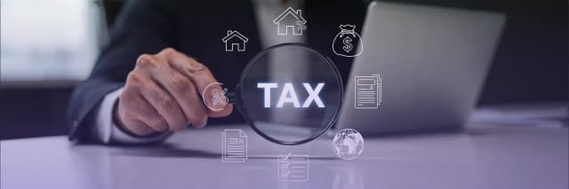 Business professional analyzing tax compliance and financial obligations through a magnifying glass with digital tax and accounting icons