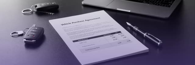 Vehicle purchase agreement document with car keys and pen on desk during car buying process.