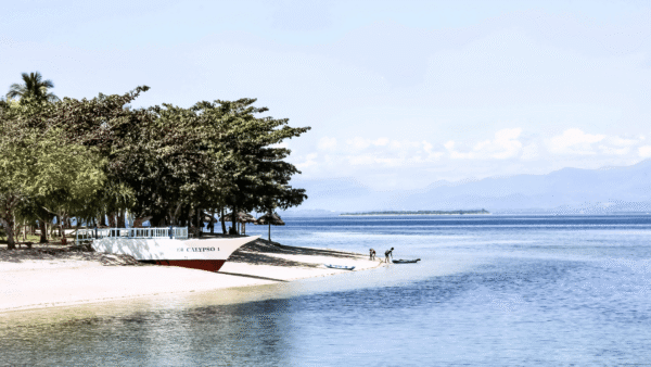 A boat parked on the shore of a beach.
