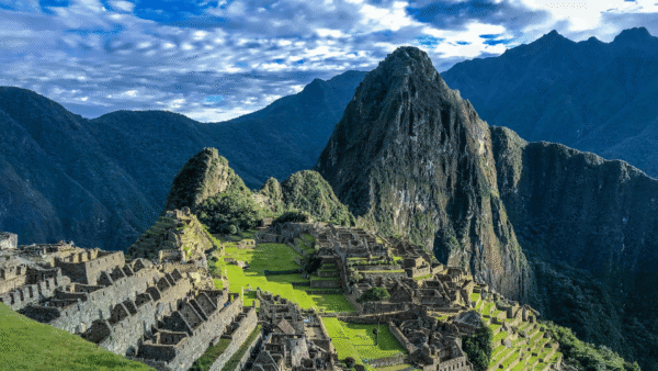 View of Machu Picchu ruins in Peru, showcasing ancient stone structures against a backdrop of lush green mountains
