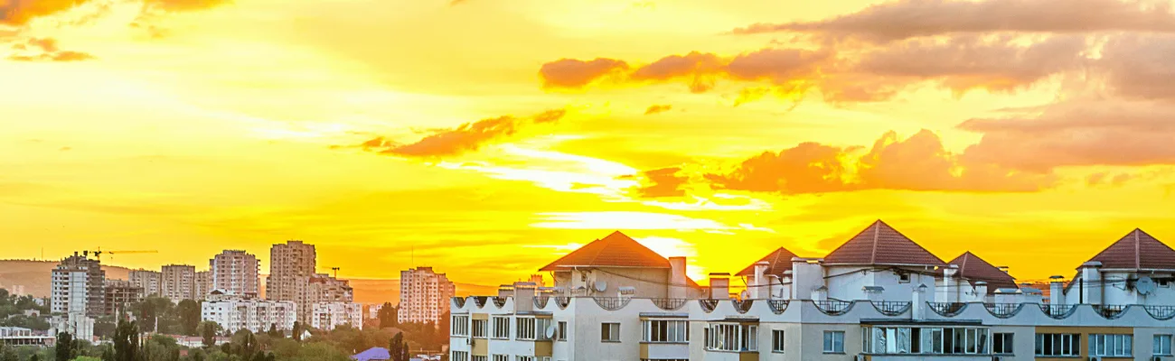 sunset casts warm hues over a city skyline, featuring a prominent clock tower in the background